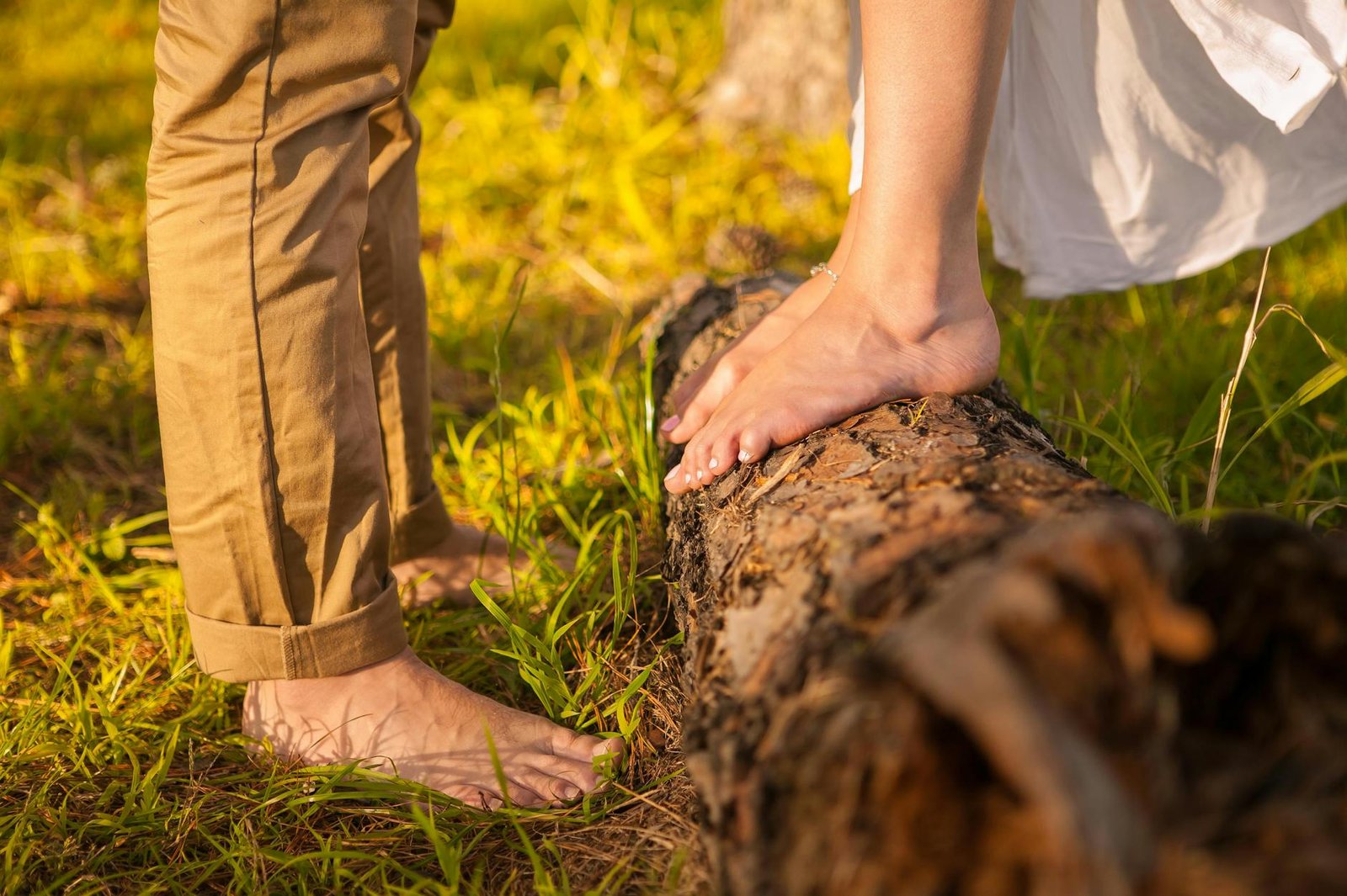 couples barefoot on the grass and log