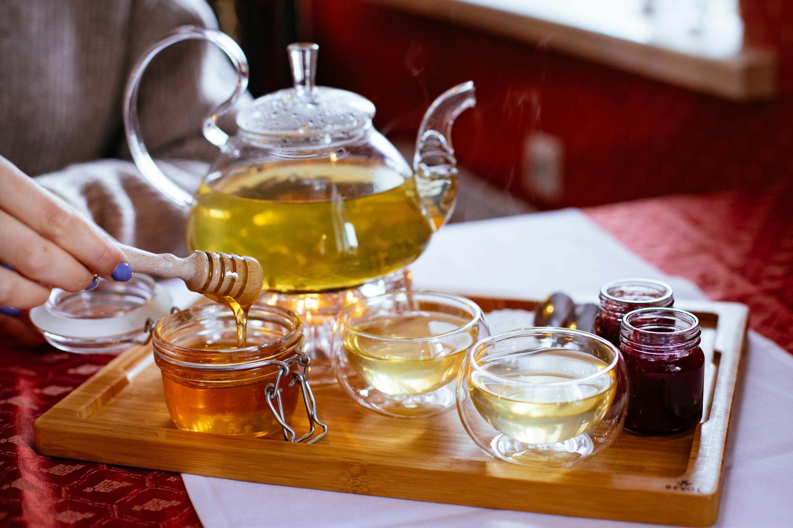 person holding honey stick with teapot